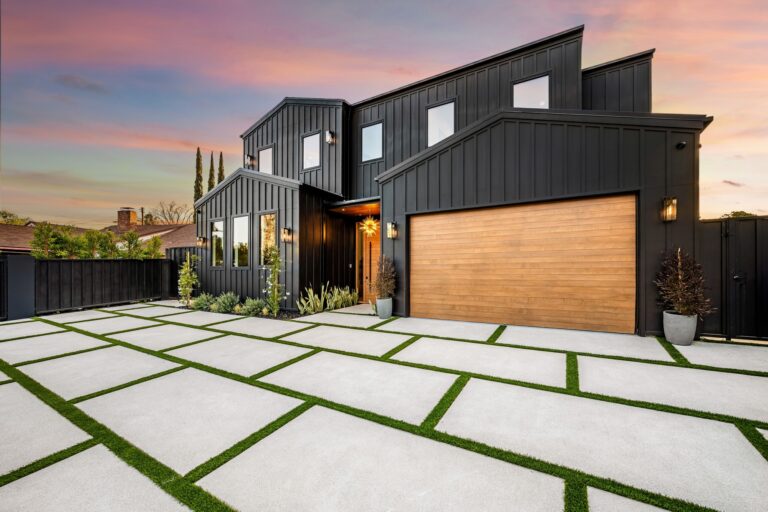 Modern black house with wooden garage door and geometric driveway.